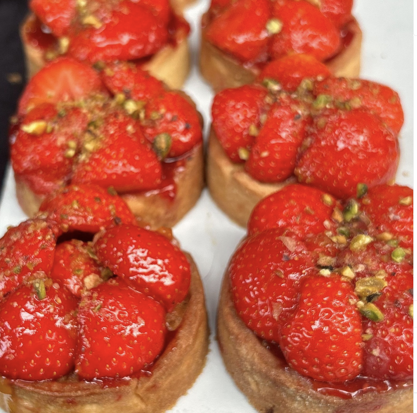 Roomboter tartelette met een vulling van frangipane en framboos met een topping van verse aardbeien en pistache nootjes